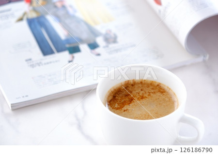 白いテーブルで、エスプレッソと牛乳を混ぜたカフェ・ラッテを飲みながら、雑誌を読んでいるイメージ 126186790