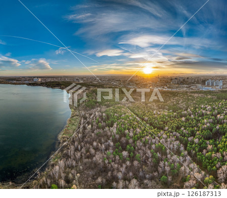 Autumn forest on lake shore at sunset and city on horizon, aerial view 126187313