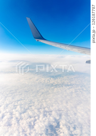 View from the airplane window at a beautiful cloudy sky and the airplane wing 126187787