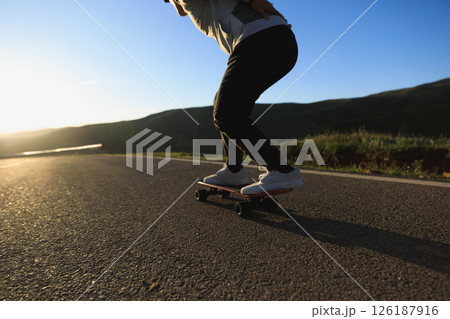 Skateboarder skateboarding on the mountain road 126187916