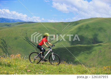 Fitness aisan woman riding mountain bike on beautiful flowering grassland mountain top 126187955