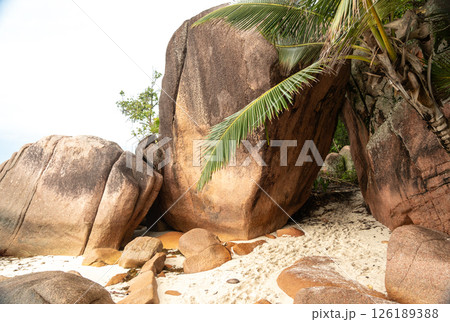 Massive granite boulders on a tropical beach of Praslin, Seychelles, with turquoise sea waves 126189388