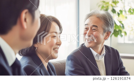 自宅のリビングで話し合うお婆さんと東洋人の男女 自宅のリビングで話し合うお婆さんと東洋人の男女 126191874