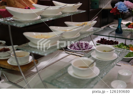 buffet sauces Various sandwich condiments in different sized glass containers and jars bunched together over gray background 126193680