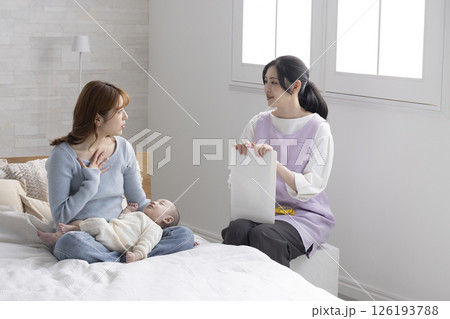 赤ちゃんを抱くお母さんと保健師さん 赤ちゃんを抱くお母さんと保健師さん 126193788