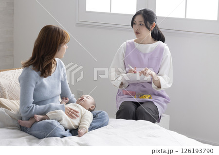 赤ちゃんを抱くお母さんと保健師さん 赤ちゃんを抱くお母さんと保健師さん 126193790