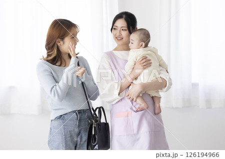 赤ちゃんを抱く保育士さんと働くママ 126194966