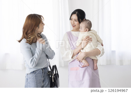 赤ちゃんを抱く保育士さんと働くママ 126194967