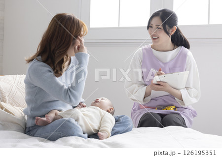 赤ちゃんを抱くお母さんと保健師さん 赤ちゃんを抱くお母さんと保健師さん 126195351