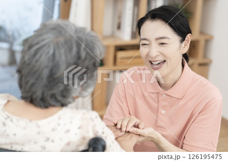 車椅子のシニア女性と話をする女性介護士 車椅子のシニア女性と話をする女性介護士 126195475