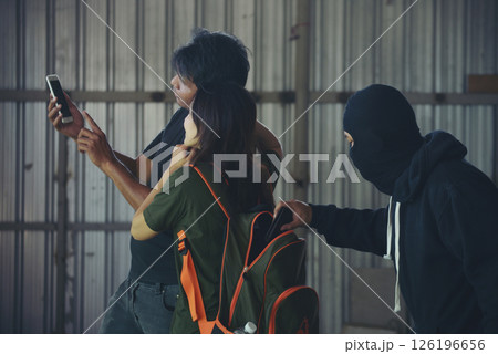 rob aggressive by danger bandit. Thief using baton nightstick weapon. Thief armed man rob woman by baton on street stalker behind young woman back. Woman on phone careless stalker sneaking to steal 126196656