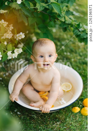 Baby Sitting In A Bowl With Citrus Slices And Water Outdoors 126196971