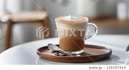 Cafe latte macchiato layered coffee in a see through coffee cup. Wooden tray with milk coffee in a transparent trendy glass mug, spoon on a white desk. Hot cappuccino coffee on table. Space for text 126197424