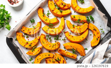 Roasted pumpkin slices with herbs placed on a heatproof plate 126197619