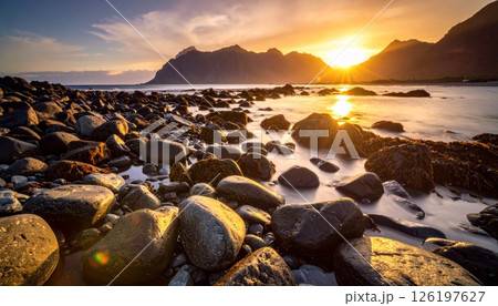 Rocky coast at sunset with mountains and river in the background. 126197627