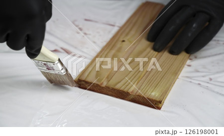 The process of Applying Wood Stain with a Brush on a Beautiful Wooden Plank Surface. Creative The process of Applying Wood Stain with a Brush on a Beautiful Wooden Plank Surface. Creative 126198001