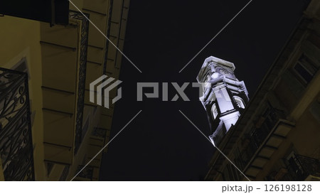 Majestic illuminated bell tower rising above buildings at night. Action 126198128