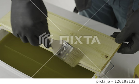 An artisan paints wood, cleans honeycomb, showcasing dedication. Creative 126198132