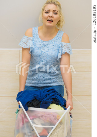 Woman holding laundry basket full of clothes 126198195