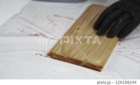 The process of Applying Wood Stain with a Brush on a Beautiful Wooden Plank Surface. Creative 126198244