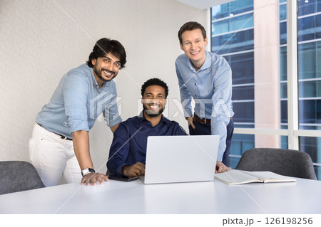 Portrait of three multinational teammates gathered around laptop Portrait of three multinational teammates gathered around laptop 126198256