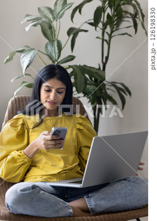 Woman zoomer relax on armchair using notebook and smartphone 126198330