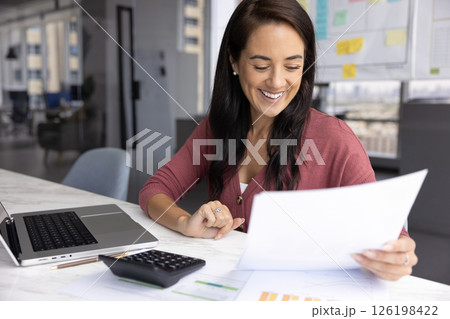 Happy smiling millennial woman bookkeeper read statistic papers at workplace 126198422
