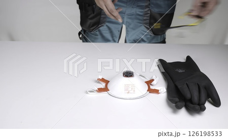 A man prepares for a task with protective gear gloves and a mask. Creative A man prepares for a task with protective gear gloves and a mask. Creative 126198533