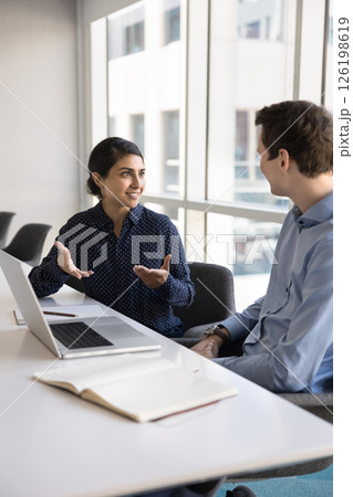 Indian professional woman explaining project details to male colleague Indian professional woman explaining project details to male colleague 126198619