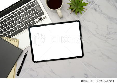 Top view of digital tablet, laptop, notebook, and coffee cup on marble desk 126198784