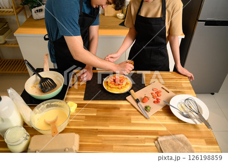 Loving young couple decorating homemade pancakes with sliced strawberries together 126198859