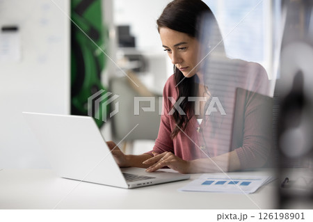 Busy young woman accountant sitting at desk working on notebook Busy young woman accountant sitting at desk working on notebook 126198901
