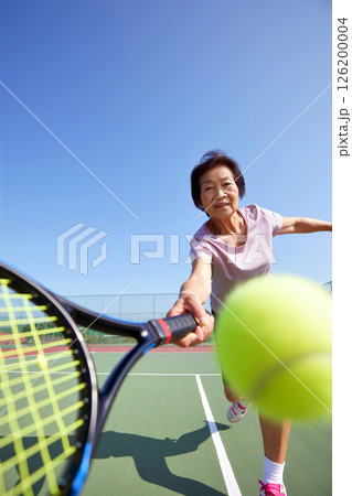 Active Senior Woman Enjoys Playing Tennis Outdoors on a Sunny Day at a Community Court 126200004