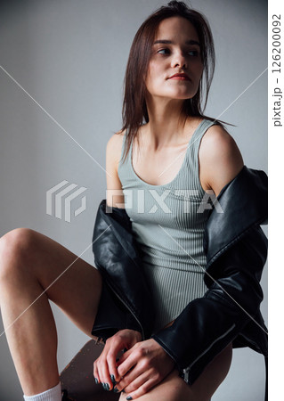Portrait of a beautiful brunette woman in a leather jacket on a gray background 126200092