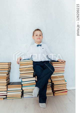 boy sitting on stacks of educational books 126200215