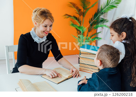 Teacher Conducting Lesson with Book for Children in School Teacher Conducting Lesson with Book for Children in School 126200218