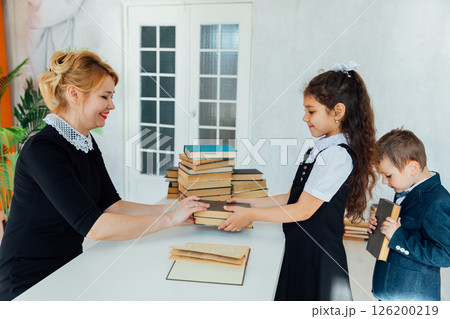 Teacher sitting at table in classroom and children Teacher sitting at table in classroom and children 126200219