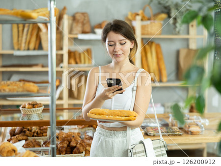 Female customer scanning QR code on label of fresh baked goods in bakery interior Female customer scanning QR code on label of fresh baked goods in bakery interior 126200912