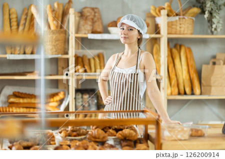 Young woman seller of bakery store is standing in trading floor, waiting for visitors 126200914