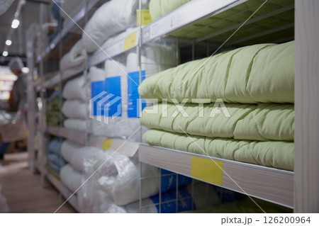 Long row of shelves packed with blankets and pillows in a store Long row of shelves packed with blankets and pillows in a store 126200964