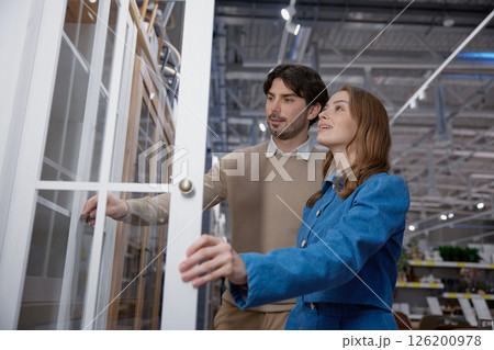 A young couple joyfully shopping for stylish furniture in a modern, vibrant store setting 126200978