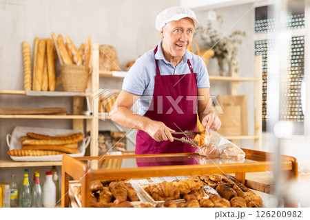 Elderly man seller puts croissants in bag 126200982
