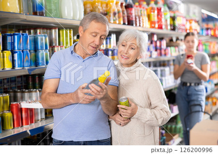 Man and woman purchasers choosing cool drink in supermarket Man and woman purchasers choosing cool drink in supermarket 126200996