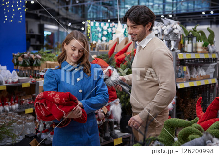 A couple enthusiastically shopping together for holiday decorations inside a store A couple enthusiastically shopping together for holiday decorations inside a store 126200998