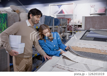 A couple happily shopping together for various home textiles and decor items in a store A couple happily shopping together for various home textiles and decor items in a store 126201019