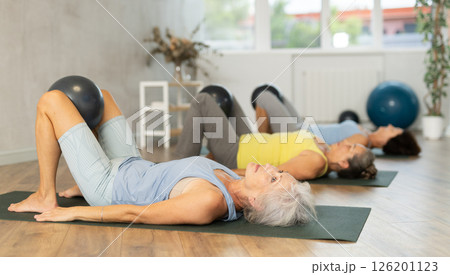 Group of elderly woman doing pilates with soft ball in studio 126201123