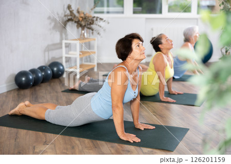 Mature lady performs asana pose dog muzzle up, Urdhva Mukha Shvanasana 126201159