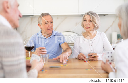 Two mature married couples playing card game poker 126201412