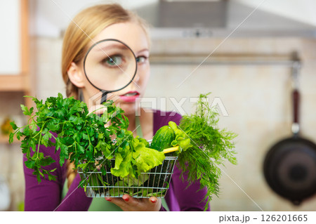 Woman looking through magnifier at vegetables basket Woman looking through magnifier at vegetables basket 126201665