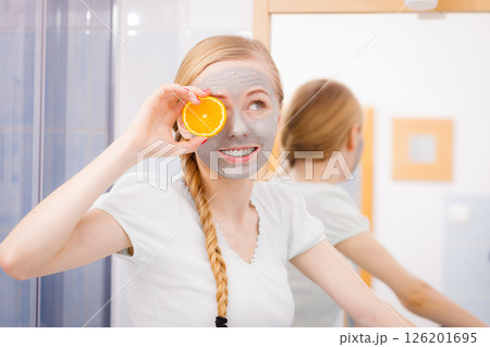 Happy young woman having face mask holding kiwi Happy young woman having face mask holding kiwi 126201695